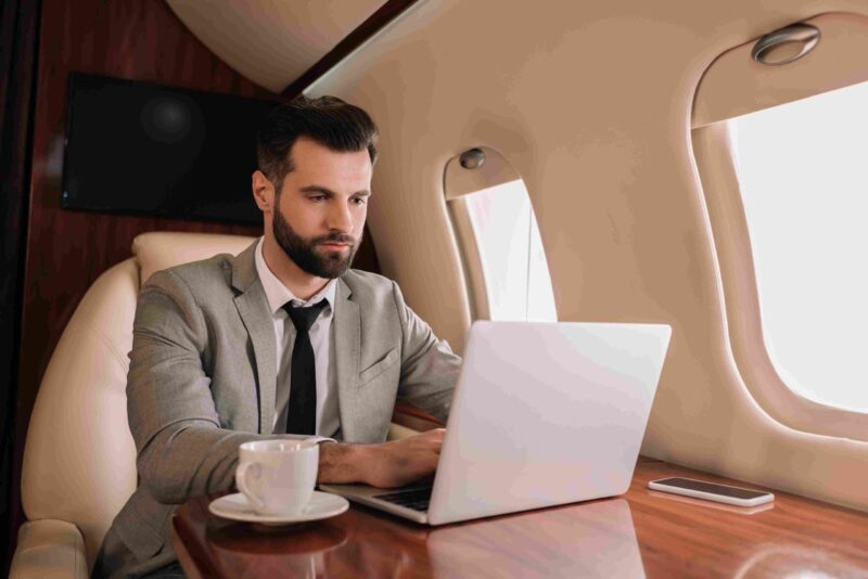 Business professional working on a laptop aboard a private jet, representing wealth, luxury lifestyles, and premium real estate markets