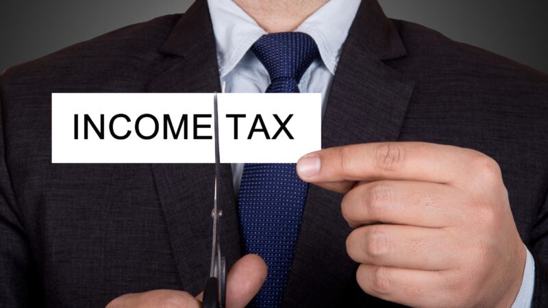 Person cuts an income tax sign with scissors