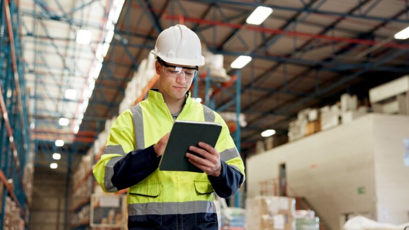 Warehouse worker using a tablet in a large logistics center